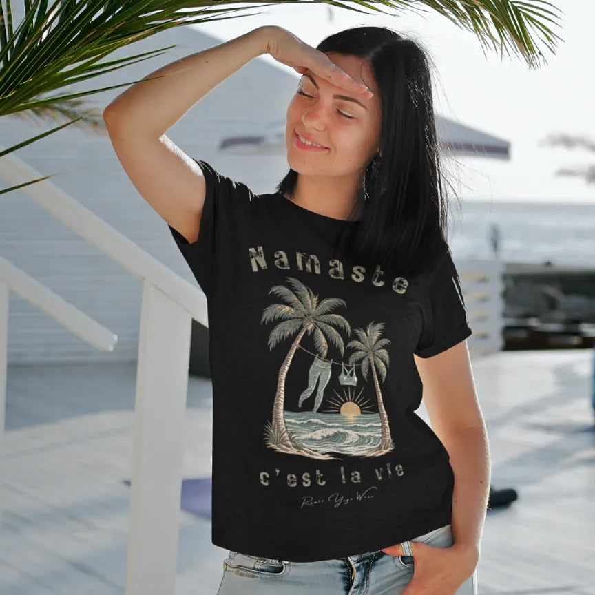 Person wearing the La Vie T-Shirt in Black, standing outdoors on a wooden deck near palm fronds — Funny Yoga Shirts collection by Ramro Yoga Wear.