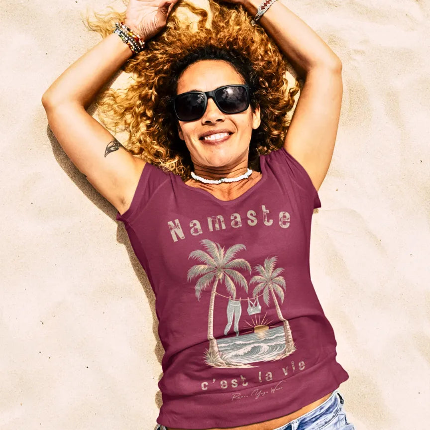 Person wearing the La Vie T-Shirt in Heather Cardinal, lying on sand with arms raised, laughing — Funny Yoga Shirts collection by Ramro Yoga Wear.