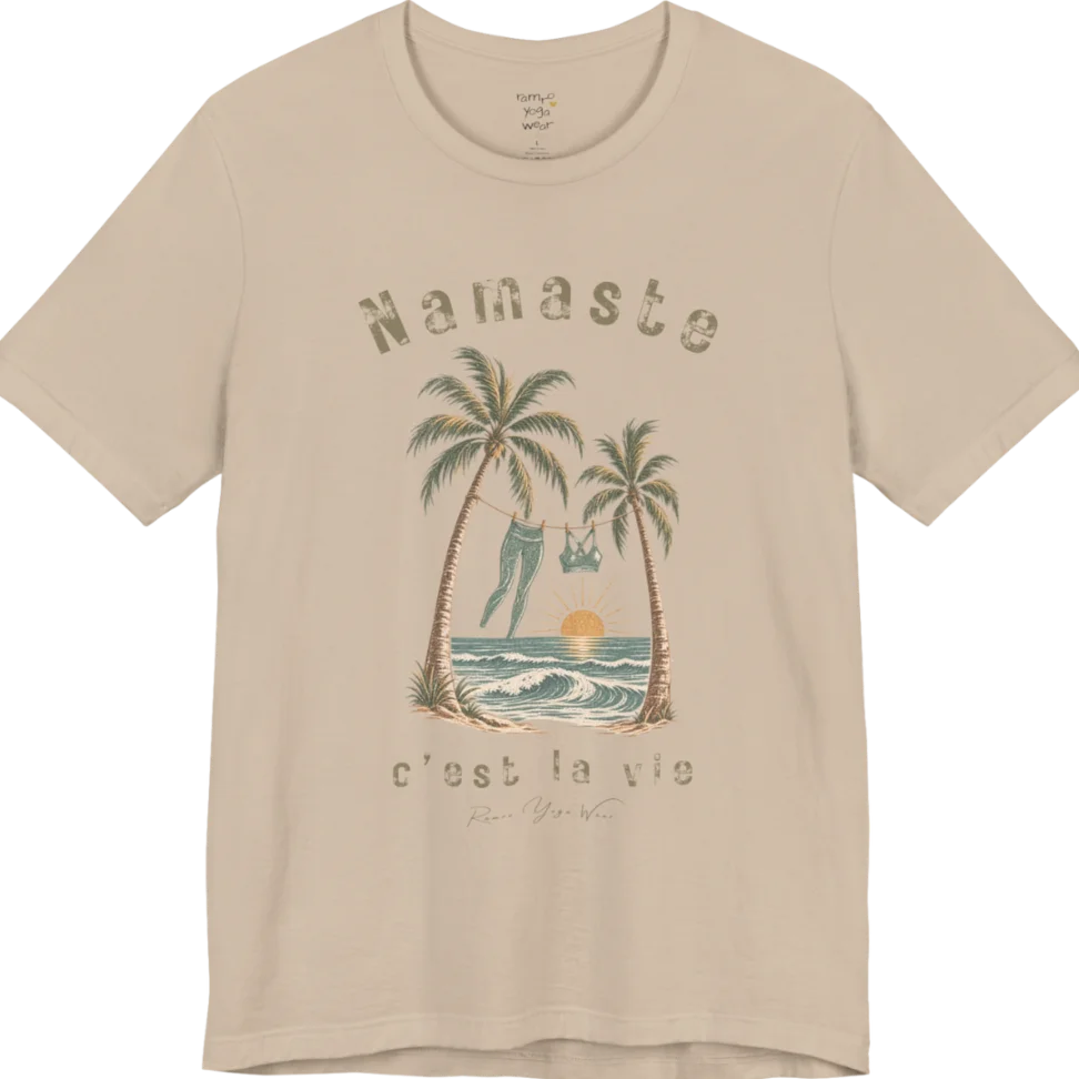 A short sleeved grunge tee with an illustrated scene of two palm trees framing a clothesline with leggings and a sports bra hanging between them, sun setting over waves, text reading "Namaste" and "c'est la vie" — Funny Yoga Shirts collection by Ramro Yoga Wear in Tan.