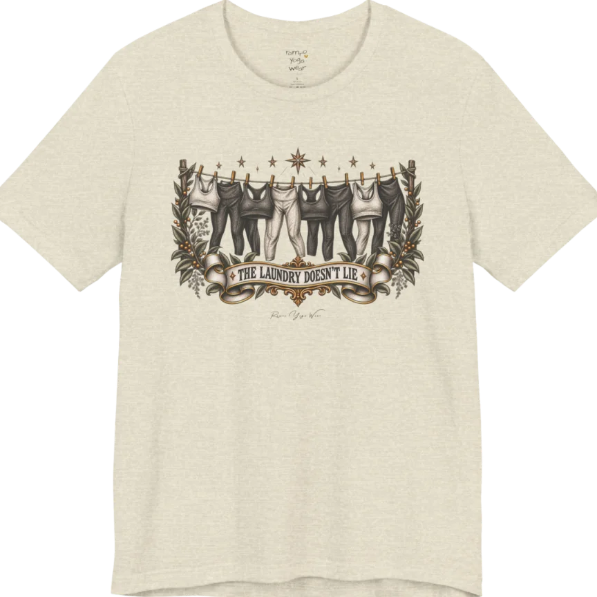 A short sleeved tee. Illustrated clothesline strung with repeating pairs of leggings and tops, framed by botanical leaf sprigs and stars. Laundry T-Shirt flat lay is a Bella+Canvas 3001 and the color is Heather Prism Natural.