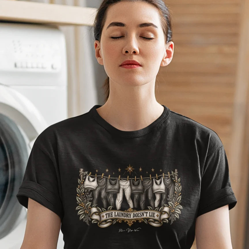 While the washing machine hums in the background a woman is in meditation pose wearing the Laundry T-Shirt. Laundry T-Shirt is a Bella+Canvas 3001 and the color is  Black.