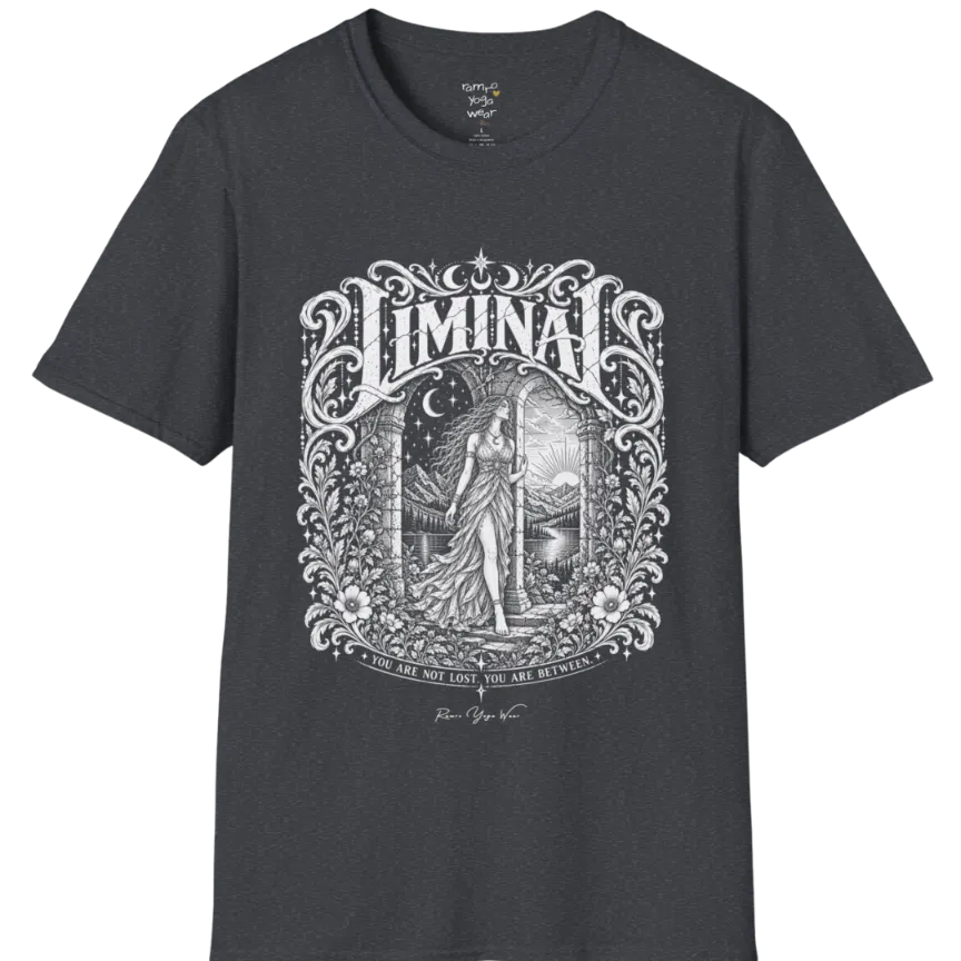 A short sleeved tee called the Liminal T-Shirt, flat lay and a soft cotton shirt. Simply says, 'You are not lost. You are between.' Design highlights ornate white LIMINAL lettering framed by flourishes and wild florals, with a robed figure standing in an arched doorway beneath a crescent moon and stars. Color is Dark Heather Grey.