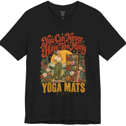 A short sleeved tee called the Mats T-Shirt, flat lay and a soft cotton shirt. Simply says, You Can Never Have Too Many Yoga Mats. Design highlights a silver-haired woman with her hand on her chin, deciding between a wooden rack of rolled yoga mats in rust, mustard, olive, teal and pink, in front of a golden sun, mountains and wildflowers in a retro travel-poster style. Color is Black.