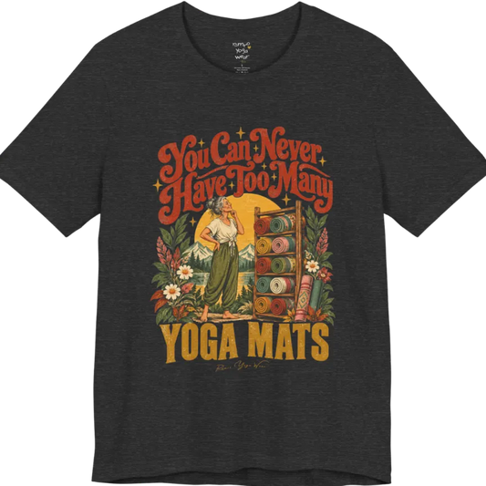 A short sleeved tee called the Mats T-Shirt, flat lay and a soft cotton shirt. Simply says, You Can Never Have Too Many Yoga Mats. Design highlights a silver-haired woman with her hand on her chin, deciding between a wooden rack of rolled yoga mats in rust, mustard, olive, teal and pink, in front of a golden sun, mountains and wildflowers in a retro travel-poster style. Color is Dark Grey Heather.