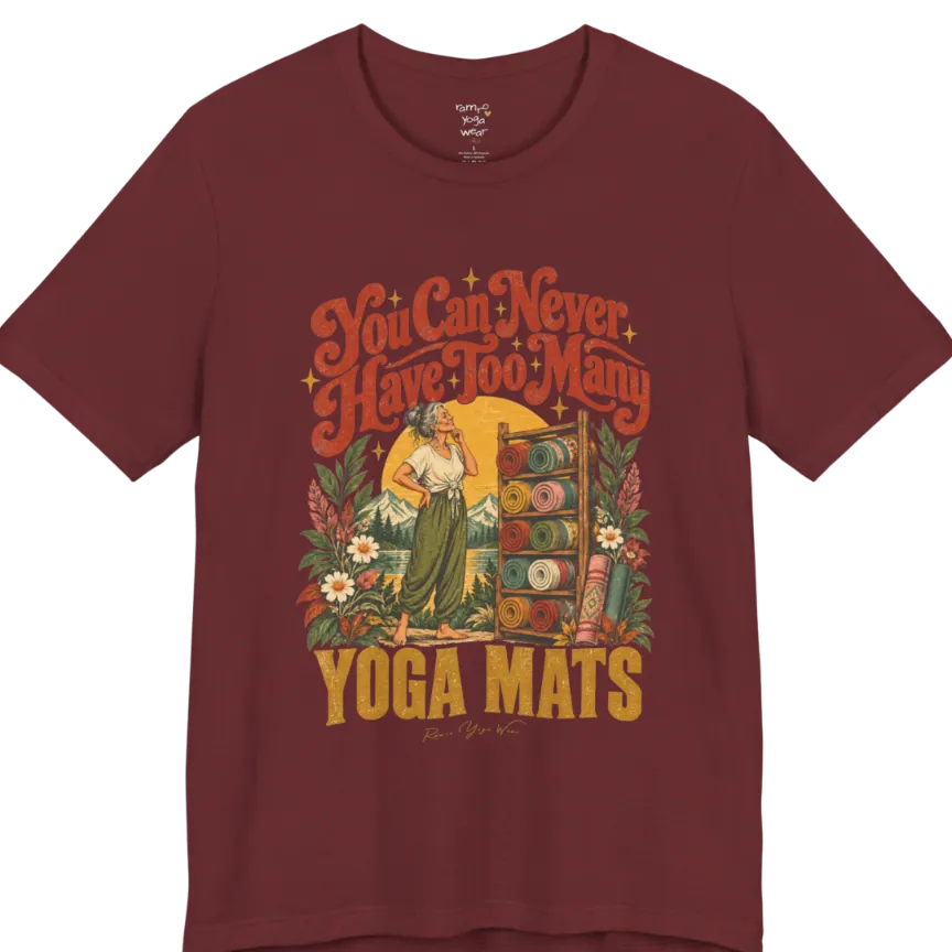 A short sleeved tee called the Mats T-Shirt, flat lay and a soft cotton shirt. Simply says, You Can Never Have Too Many Yoga Mats. Design highlights a silver-haired woman with her hand on her chin, deciding between a wooden rack of rolled yoga mats in rust, mustard, olive, teal and pink, in front of a golden sun, mountains and wildflowers in a retro travel-poster style. Color is Heather Cardinal.