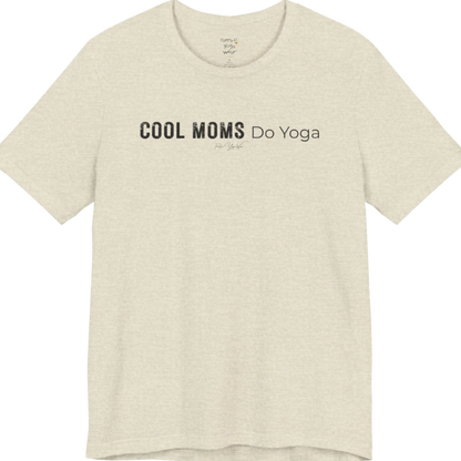 A short sleeved tee called the Moms T-Shirt, flat lay and a soft cotton shirt. Simply says, Cool Moms Do Yoga. Design highlights bold distressed block lettering for Cool Moms beside lighter thin lettering for Do Yoga, with a small script signature underneath. Color is Heather Prism Natural.