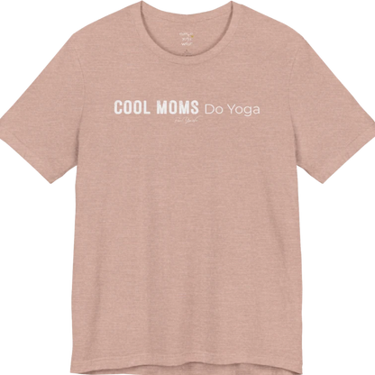 A short sleeved tee called the Moms T-Shirt, flat lay and a soft cotton shirt. Simply says, Cool Moms Do Yoga. Design highlights bold distressed block lettering for Cool Moms beside lighter thin lettering for Do Yoga, with a small script signature underneath. Color is Heather Prism Peach.