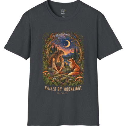 A short sleeved tee called the Moonlight T-Shirt, flat lay and a Gildan 64000 shirt. Simply says, Raised By Moonlight. Design highlights a woman sitting cross-legged in a moonlit forest clearing with a fox beside her, surrounded by mushrooms and ferns, in a full-color painted illustration style. Color is Dark Heather Grey.