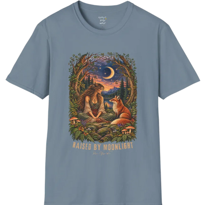 A short sleeved tee called the Moonlight T-Shirt, flat lay and a Gildan 64000 shirt. Simply says, Raised By Moonlight. Design highlights a woman sitting cross-legged in a moonlit forest clearing with a fox beside her, surrounded by mushrooms and ferns, in a full-color painted illustration style. Color is Stone Blue.
