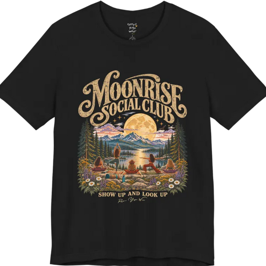 A short sleeved tee called the Moonrise T-Shirt, flat lay and a Bella+Canvas 3001. Simply says, Moonrise Social Club. Show Up And Look Up. Design highlights five women seen from behind practicing yoga on a rocky lakeside shelf, one in tree pose, one in warrior pose and three seated, beneath a glowing full moon rising over snow-capped mountains, framed by pine trees and wildflowers. Color is Black.
