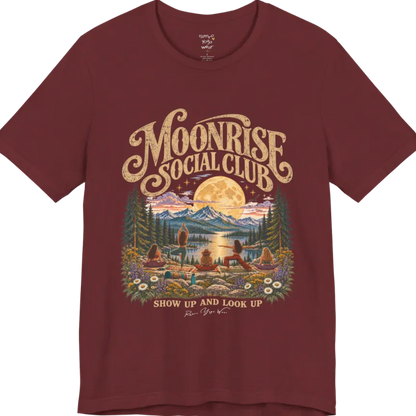 A short sleeved tee called the Moonrise T-Shirt, flat lay and a Bella+Canvas 3001. Simply says, Moonrise Social Club. Show Up And Look Up. Design highlights five women seen from behind practicing yoga on a rocky lakeside shelf, one in tree pose, one in warrior pose and three seated, beneath a glowing full moon rising over snow-capped mountains, framed by pine trees and wildflowers. Color is Heather Cardinal.
