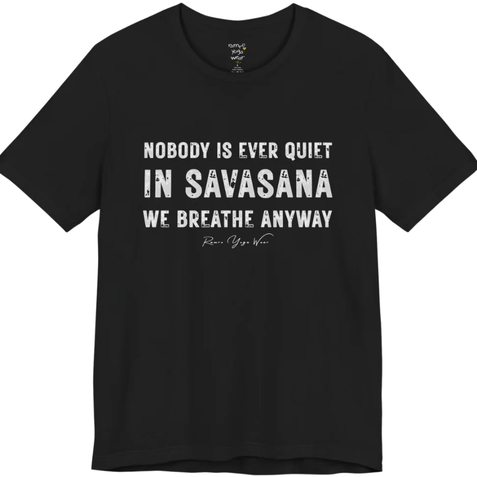 A short sleeved tee called the Nobody T-Shirt, flat lay and a soft cotton shirt. Simply says, Nobody is ever quiet in savasana. We breathe anyway. Design highlights three lines of bold condensed cream lettering with a small handwritten signature beneath. Color is Black.