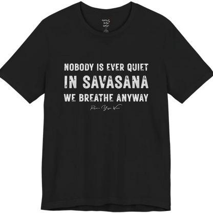 A short sleeved tee called the Nobody T-Shirt, flat lay and a soft cotton shirt. Simply says, Nobody is ever quiet in savasana. We breathe anyway. Design highlights three lines of bold condensed cream lettering with a small handwritten signature beneath. Color is Black.
