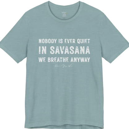 A short sleeved tee called the Nobody T-Shirt, flat lay and a soft cotton shirt. Simply says, Nobody is ever quiet in savasana. We breathe anyway. Design highlights three lines of bold condensed cream lettering with a small handwritten signature beneath. Color is Blue Lagoon.