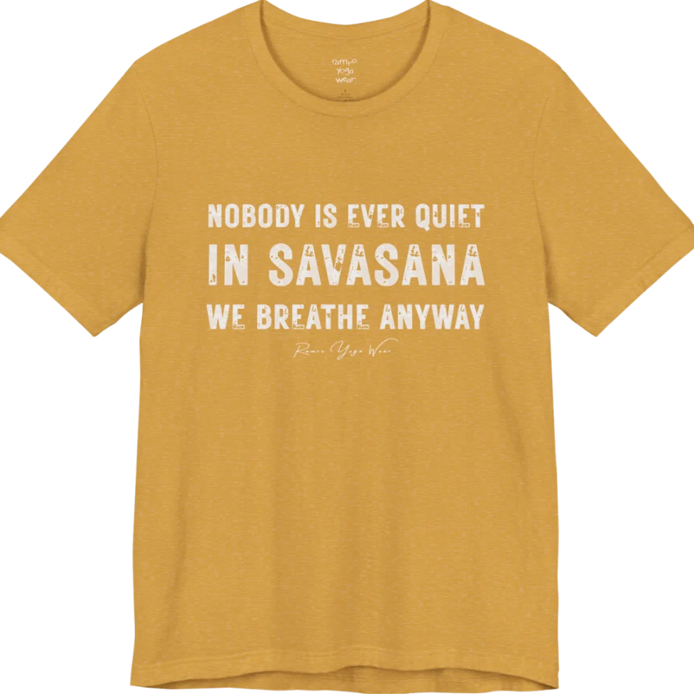 A short sleeved tee called the Nobody T-Shirt, flat lay and a soft cotton shirt. Simply says, Nobody is ever quiet in savasana. We breathe anyway. Design highlights three lines of bold condensed cream lettering with a small handwritten signature beneath. Color is Heather Mustard.
