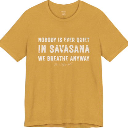 A short sleeved tee called the Nobody T-Shirt, flat lay and a soft cotton shirt. Simply says, Nobody is ever quiet in savasana. We breathe anyway. Design highlights three lines of bold condensed cream lettering with a small handwritten signature beneath. Color is Heather Mustard.