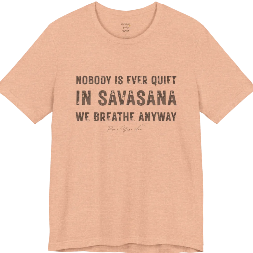 A short sleeved tee called the Nobody T-Shirt, flat lay and a soft cotton shirt. Simply says, Nobody is ever quiet in savasana. We breathe anyway. Design highlights three lines of bold condensed cream lettering with a small handwritten signature beneath. Color is Heather Peach.