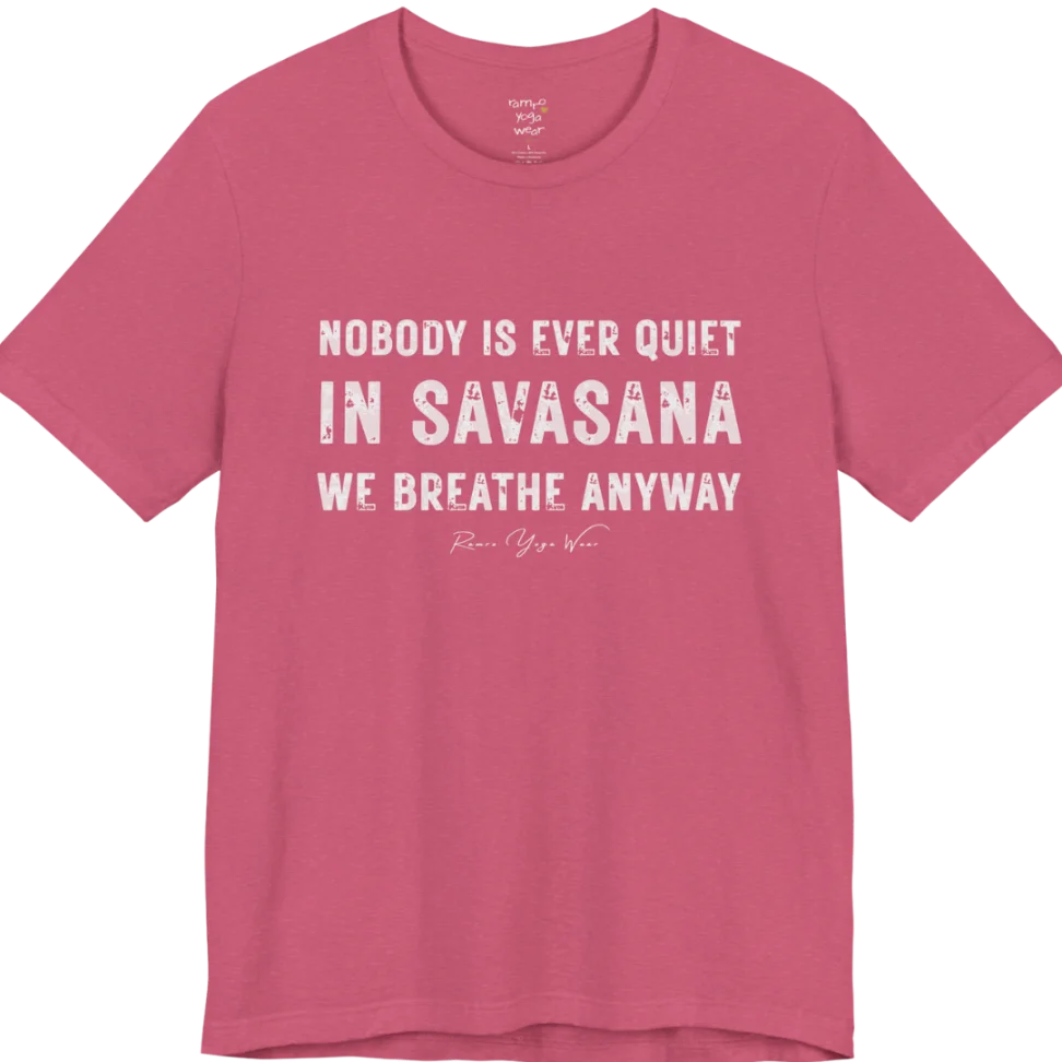 A short sleeved tee called the Nobody T-Shirt, flat lay and a soft cotton shirt. Simply says, Nobody is ever quiet in savasana. We breathe anyway. Design highlights three lines of bold condensed cream lettering with a small handwritten signature beneath. Color is Heather Raspberry.