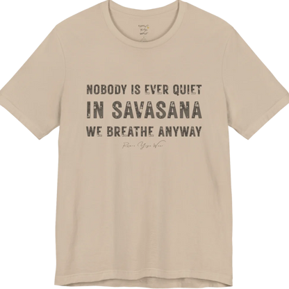A short sleeved tee called the Nobody T-Shirt, flat lay and a soft cotton shirt. Simply says, Nobody is ever quiet in savasana. We breathe anyway. Design highlights three lines of bold condensed cream lettering with a small handwritten signature beneath. Color is Tan.