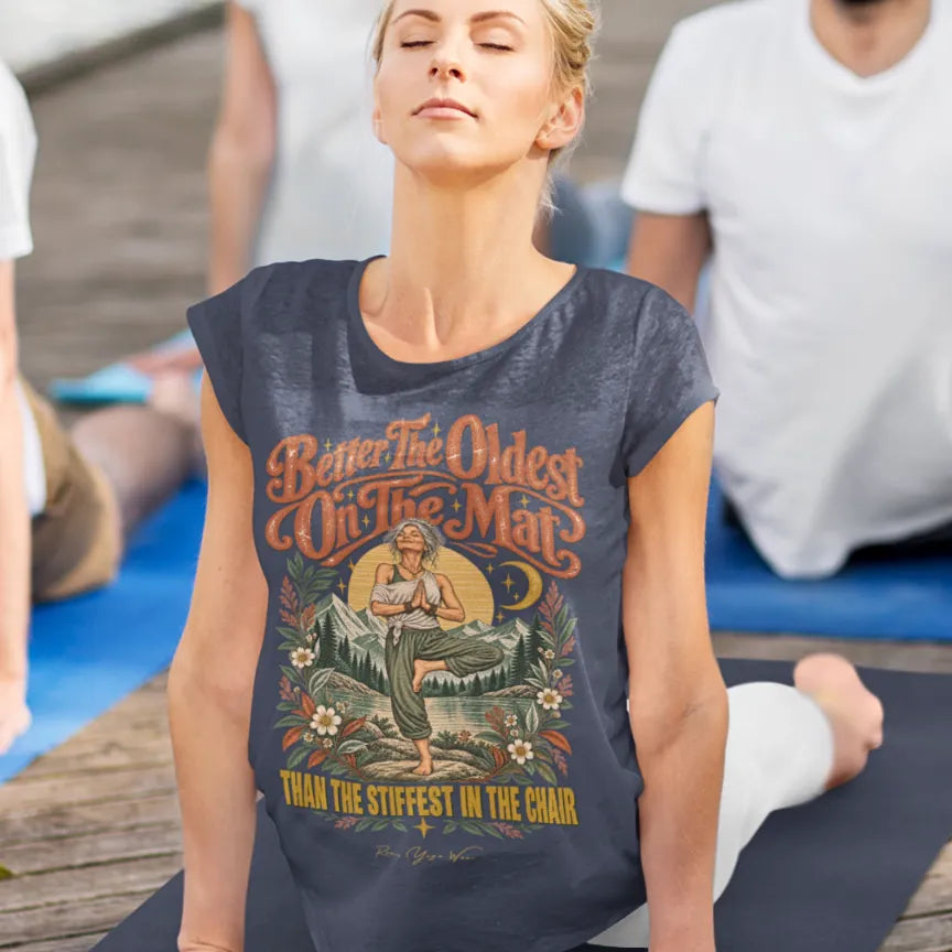 A woman is in Cobra Pose with her eyes closed at her yoga class, other participants around her, wearing the Oldest T-Shirt. Oldest T-Shirt is a Bella+Canvas 3001 and the color is Heather Midnight Navy.