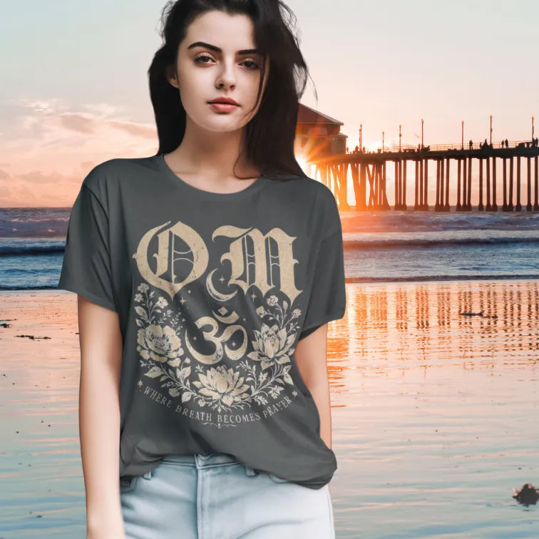 Woman wearing dark heather grey  Om T-Shirt in relaxed outdoor setting with grounded editorial yoga lifestyle styling.