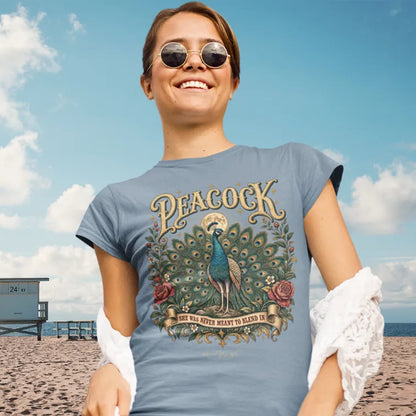 Person wearing Peacock Stone Blue tee, smiling outdoors on a beach in sunglasses — Wild Animals collection by Ramro Yoga Wear