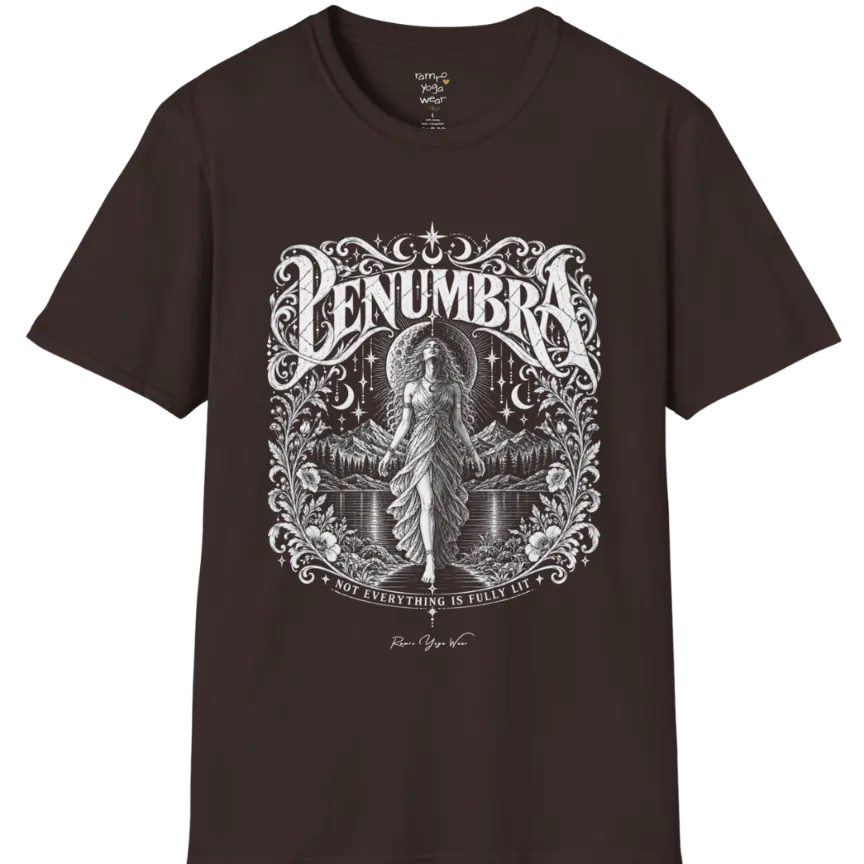 A short sleeved tee called the Penumbra T-Shirt, flat lay and a Gildan 64000 shirt. Simply says, Not Everything Is Fully Lit. Design highlights a moon goddess bathed in radiant light against a mountain backdrop, framed in ornate vintage lettering with botanical detailing. Color is Dark Chocolate.