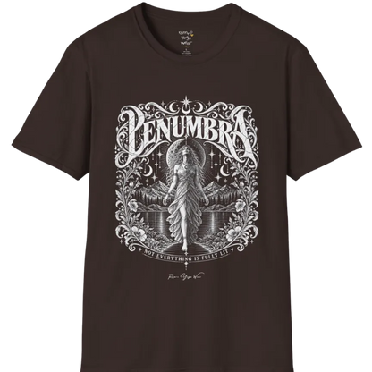 A short sleeved tee called the Penumbra T-Shirt, flat lay and a Gildan 64000 shirt. Simply says, Not Everything Is Fully Lit. Design highlights a moon goddess bathed in radiant light against a mountain backdrop, framed in ornate vintage lettering with botanical detailing. Color is Dark Chocolate.