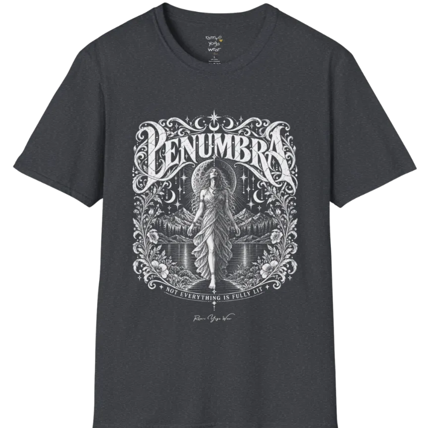 A short sleeved tee called the Penumbra T-Shirt, flat lay and a Gildan 64000 shirt. Simply says, Not Everything Is Fully Lit. Design highlights a moon goddess bathed in radiant light against a mountain backdrop, framed in ornate vintage lettering with botanical detailing. Color is Dark Heather Grey.