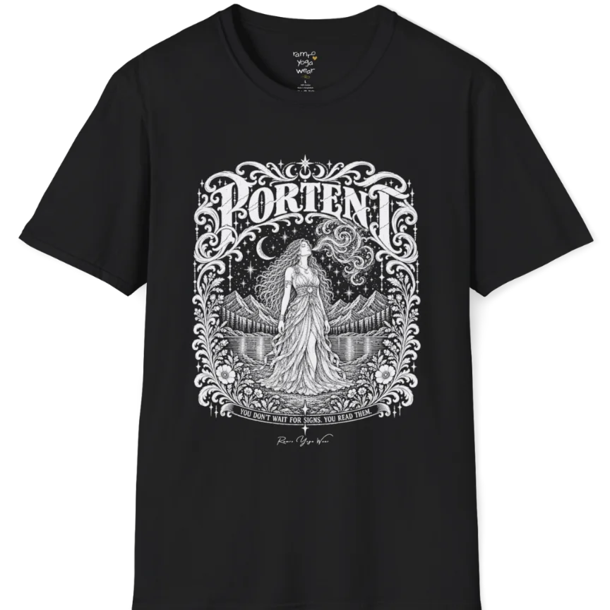 A short sleeved tee called the Portent T-Shirt, flat lay and a soft cotton shirt. Simply says, You don't wait for signs. You read them. Design highlights an ornate engraved frame of florals and filigree around a long-haired figure in a flowing gown standing before mountains and still water, with a crescent moon, stars and swirling smoke above and Portent in decorative lettering across the top. Color is Black.