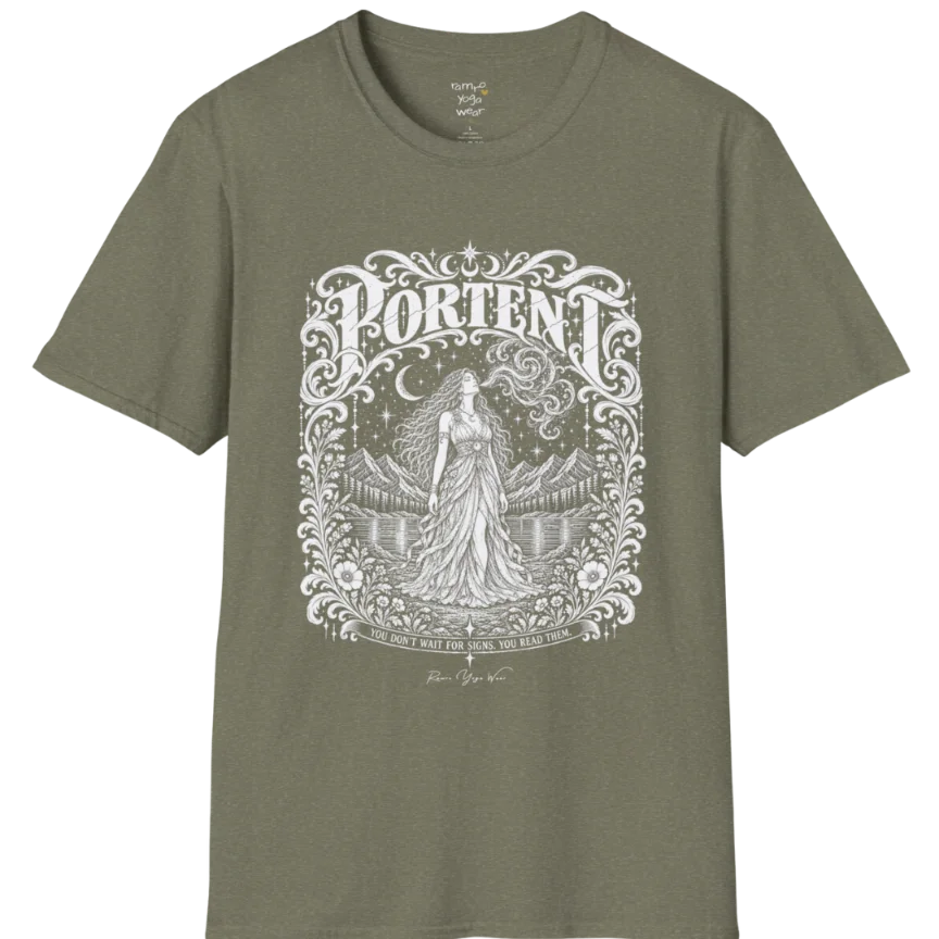 A short sleeved tee called the Portent T-Shirt, flat lay and a soft cotton shirt. Simply says, You don't wait for signs. You read them. Design highlights an ornate engraved frame of florals and filigree around a long-haired figure in a flowing gown standing before mountains and still water, with a crescent moon, stars and swirling smoke above and Portent in decorative lettering across the top. Color is Heather Military Green.