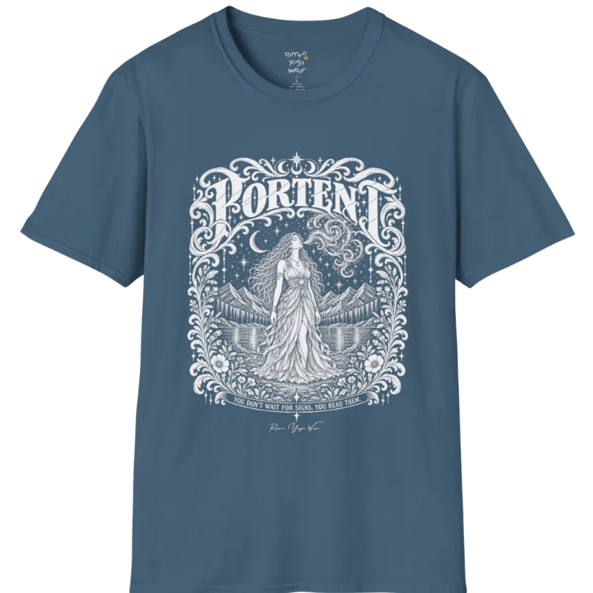 A short sleeved tee called the Portent T-Shirt, flat lay and a soft cotton shirt. Simply says, You don't wait for signs. You read them. Design highlights an ornate engraved frame of florals and filigree around a long-haired figure in a flowing gown standing before mountains and still water, with a crescent moon, stars and swirling smoke above and Portent in decorative lettering across the top. Color is Indigo Blue.