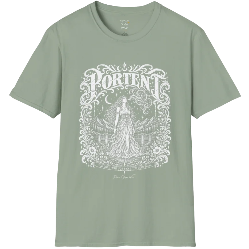 A short sleeved tee called the Portent T-Shirt, flat lay and a soft cotton shirt. Simply says, You don't wait for signs. You read them. Design highlights an ornate engraved frame of florals and filigree around a long-haired figure in a flowing gown standing before mountains and still water, with a crescent moon, stars and swirling smoke above and Portent in decorative lettering across the top. Color is Sage.