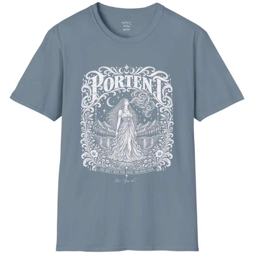 A short sleeved tee called the Portent T-Shirt, flat lay and a soft cotton shirt. Simply says, You don't wait for signs. You read them. Design highlights an ornate engraved frame of florals and filigree around a long-haired figure in a flowing gown standing before mountains and still water, with a crescent moon, stars and swirling smoke above and Portent in decorative lettering across the top. Color is Stone Blue.