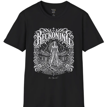 A short sleeved tee called the Reckoning T-Shirt, flat lay and a soft cotton shirt. Simply says, A reckoning, not a retreat. Design highlights ornate white RECKONING lettering framed by flourishes and wild florals, with a long-haired figure in a flowing gown walking a footprint path toward a lightning storm over mountains and a lake. Color is Black.