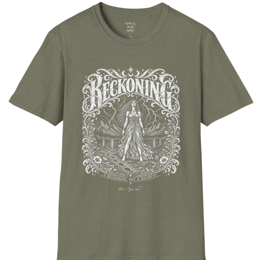 A short sleeved tee called the Reckoning T-Shirt, flat lay and a soft cotton shirt. Simply says, A reckoning, not a retreat. Design highlights ornate white RECKONING lettering framed by flourishes and wild florals, with a long-haired figure in a flowing gown walking a footprint path toward a lightning storm over mountains and a lake. Color is Heather Military Green.