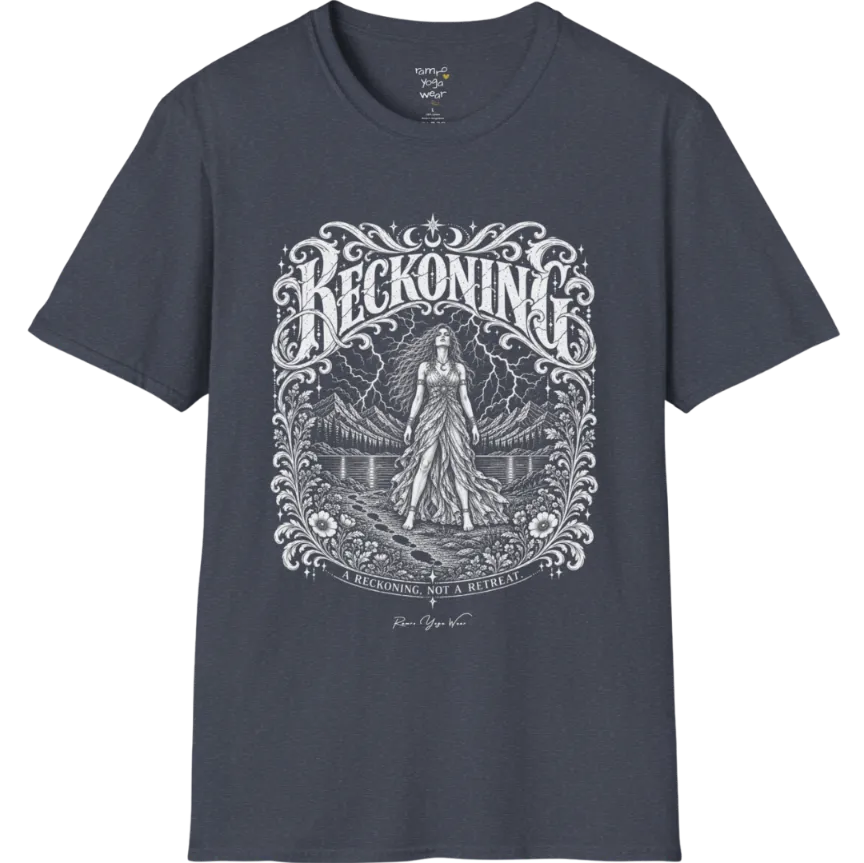 A short sleeved tee called the Reckoning T-Shirt, flat lay and a soft cotton shirt. Simply says, A reckoning, not a retreat. Design highlights ornate white RECKONING lettering framed by flourishes and wild florals, with a long-haired figure in a flowing gown walking a footprint path toward a lightning storm over mountains and a lake. Color is Heather Navy.