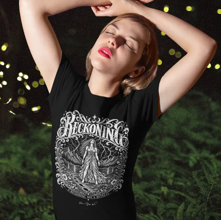 Person with arms raised over their head, eyes closed, wearing a black Reckoning T-Shirt with ornate white lettering and a figure beneath a lightning storm, in a dark garden at night.