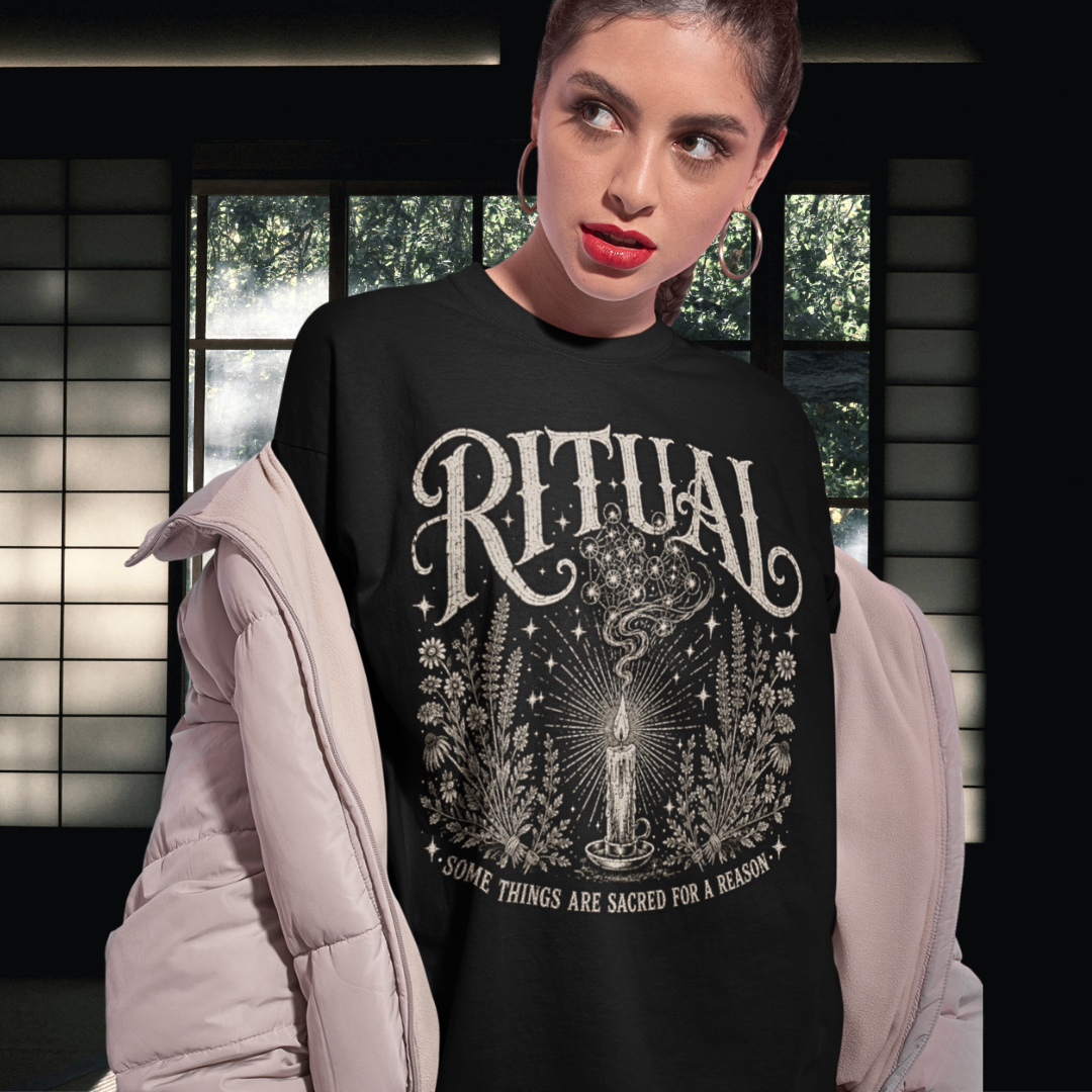 Person wearing the Ritual T-Shirt in black, a sacred yoga shirt at home by a curtained window in the evening — Wild Devotion collection by Ramro Yoga Wear