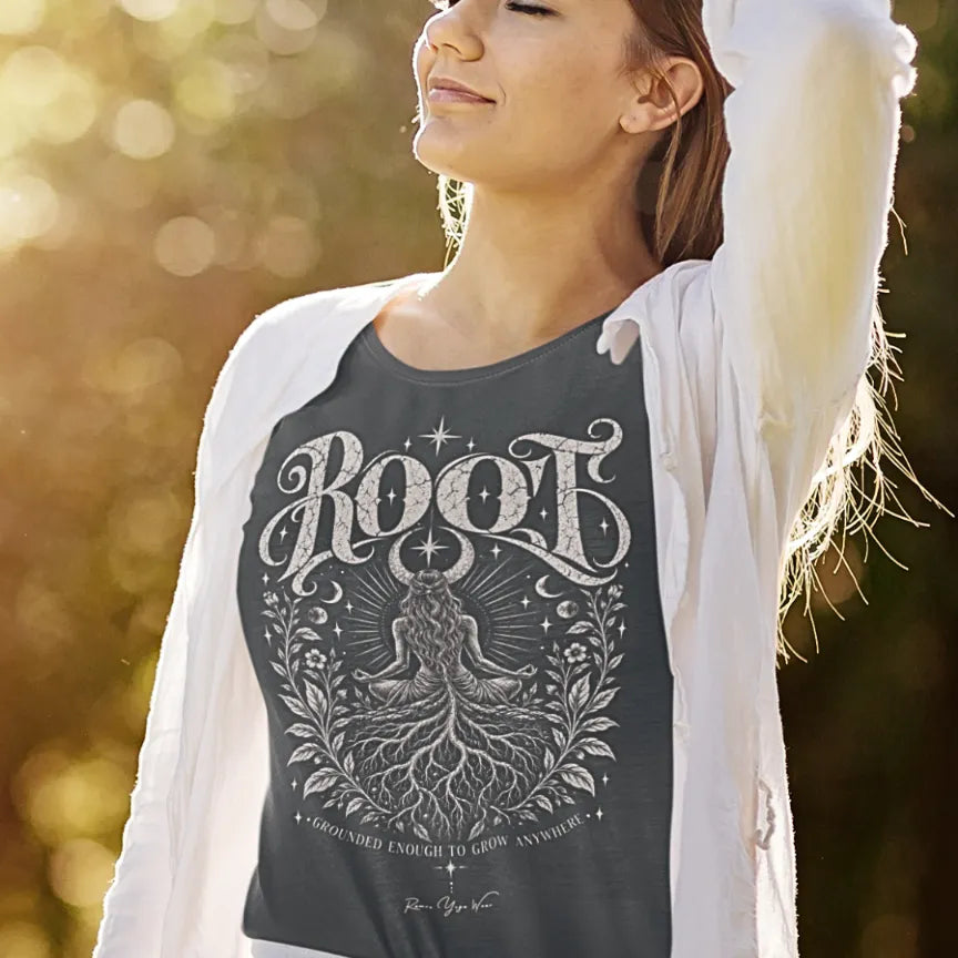 A woman stretches with her head tilted back in golden backlight, wearing a white cardigan over the Root T-Shirt. Root T-Shirt is a Gildan 64000 and the color is Dark Heather Grey.