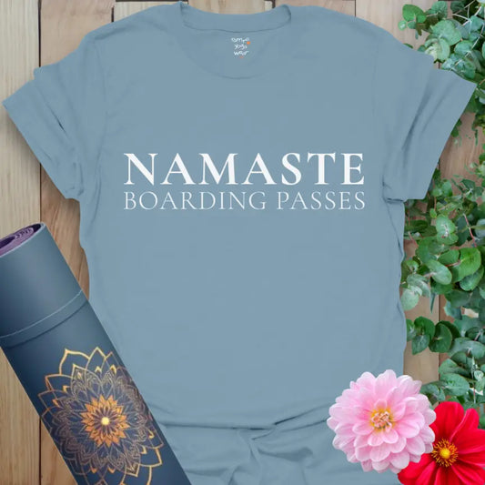 Stone Blue Boarding Passes T-Shirt with refined serif typography reading "NAMASTE Boarding Passes." Yoga-inspired travel tee styled with florals and mat.