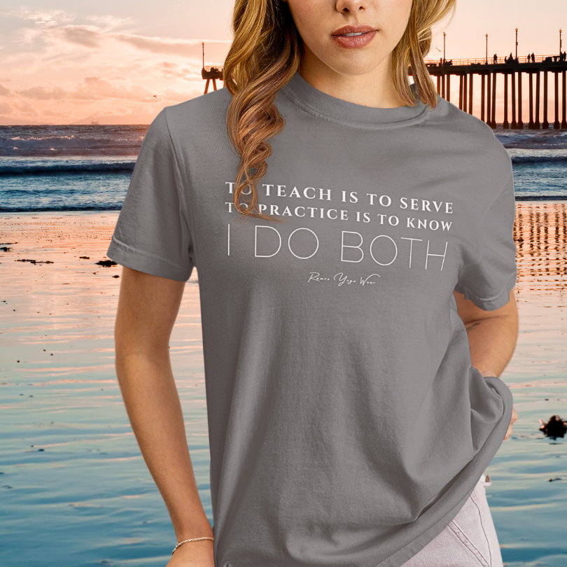 Woman wearing Sacred Work Storm yoga teacher gift tee on the beach at sunset near a pier — Yoga Teacher Gifts collection by Ramro Yoga Wear