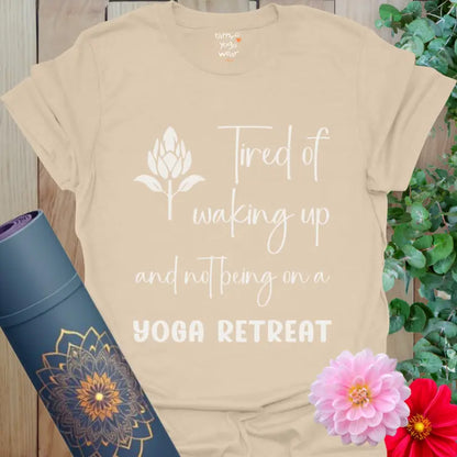 Sand Yoga Retreat T-Shirt with script and bold lettering saying “Tired of waking up and not being on a YOGA RETREAT.” Soft yoga graphic design.