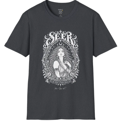A short sleeved tee called the Seer T-Shirt, flat lay and a soft cotton blend shirt. Simply says, You see what others walk past. Design highlights an ornate engraved almond-shaped frame of florals and filigree around a close portrait of a long-haired figure with a star on the brow, crescent moon earrings and one hand at the collarbone, beneath a crescent moon and hanging stars, with Seer in decorative lettering across the top and the tagline on a banner below. Color is Dark Heather Grey.