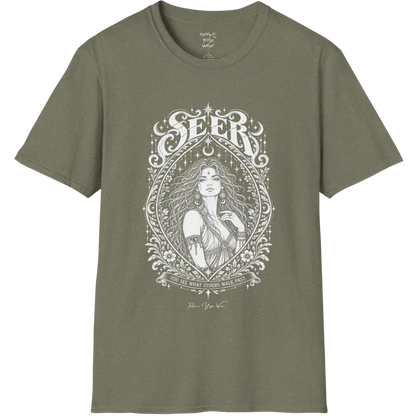 A short sleeved tee called the Seer T-Shirt, flat lay and a soft cotton blend shirt. Simply says, You see what others walk past. Design highlights an ornate engraved almond-shaped frame of florals and filigree around a close portrait of a long-haired figure with a star on the brow, crescent moon earrings and one hand at the collarbone, beneath a crescent moon and hanging stars, with Seer in decorative lettering across the top and the tagline on a banner below. Color is Heather Military Green.