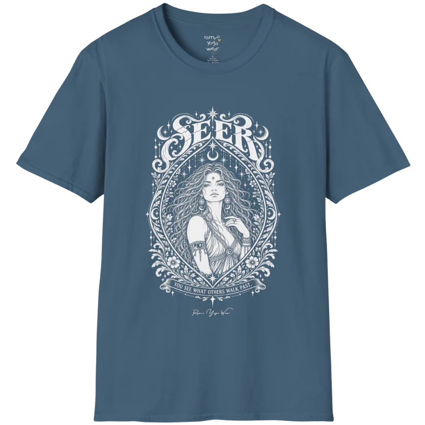 A short sleeved tee called the Seer T-Shirt, flat lay and a soft cotton shirt. Simply says, You see what others walk past. Design highlights an ornate engraved almond-shaped frame of florals and filigree around a close portrait of a long-haired figure with a star on the brow, crescent moon earrings and one hand at the collarbone, beneath a crescent moon and hanging stars, with Seer in decorative lettering across the top and the tagline on a banner below. Color is Indigo Blue.