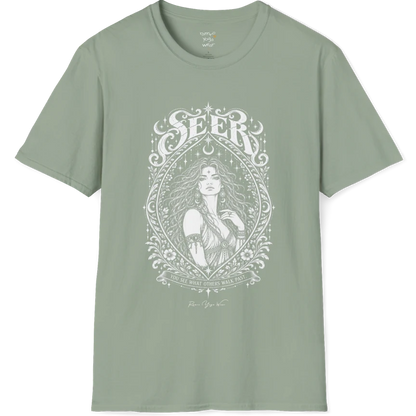 A short sleeved tee called the Seer T-Shirt, flat lay and a soft cotton shirt. Simply says, You see what others walk past. Design highlights an ornate engraved almond-shaped frame of florals and filigree around a close portrait of a long-haired figure with a star on the brow, crescent moon earrings and one hand at the collarbone, beneath a crescent moon and hanging stars, with Seer in decorative lettering across the top and the tagline on a banner below. Color is Sage.