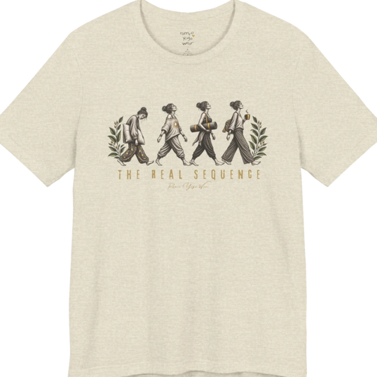 Four illustrated figures walking in sequence — pillow, sunburst top, rolled yoga mat, and coffee cup — framed by botanical leaf sprigs. Sequence T-Shirt flat lay is a Bella+Canvas 3001 and the color is Heather Prism Natural.