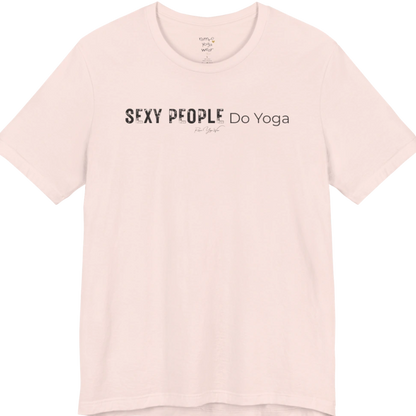 A short sleeved tee called the Sexy T-Shirt, flat lay and a soft cotton shirt. Simply says, Sexy People Do Yoga. Design highlights bold distressed block lettering for Sexy People beside lighter thin lettering for Do Yoga, with a small script signature underneath. Color is Soft Pink.