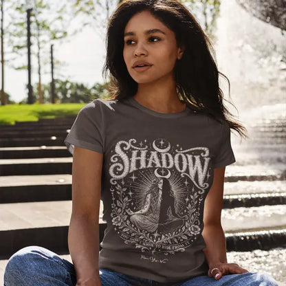 Woman wearing Shadow T-Shirt seated outdoors near a fountain, shirt in Dark Chocolate.